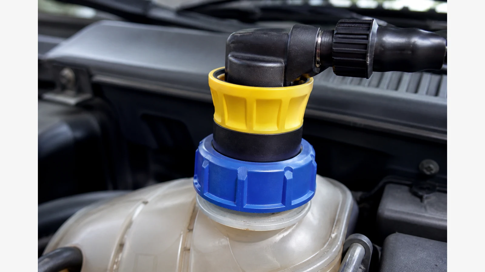 Colour-coded radiator adapter fitted to an expansion tank for a DIY pressure test